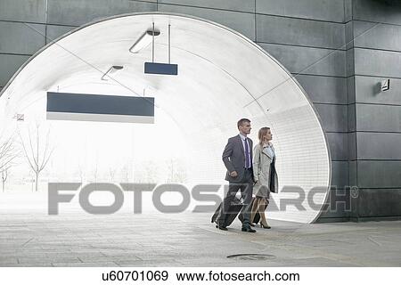 Stock Photo - Businessman and businesswoman entering railroad station. Fotosearch