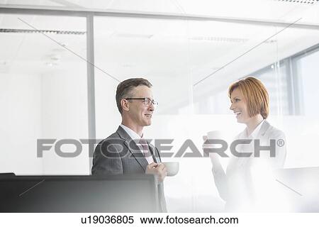 Businessman and businesswoman having coffee in office View Large Photo Image Stock Photography - Businessman and businesswoman having coffee in office. Fotosearch