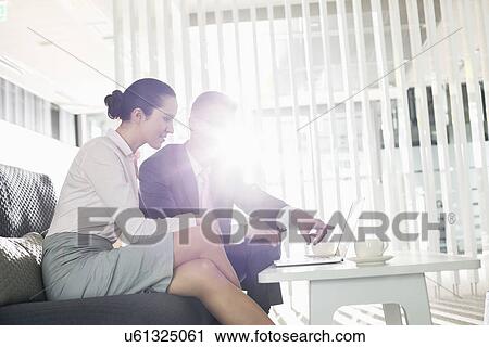 Stock Image - Businessman and businesswoman discussing over laptop in office. Fotosearch