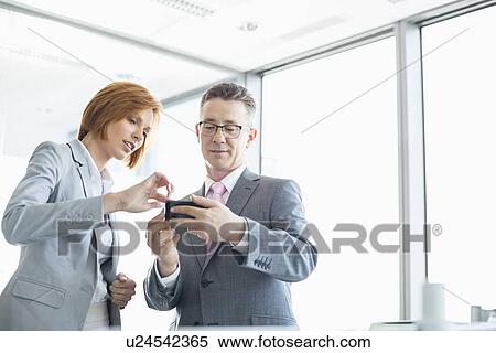 Stock Photography - Businessman and businesswoman using cell people in office. Fotosearch