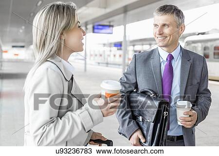 Businessman and businesswoman with coffee cups talking at railroad platform View Large Photo Image Stock Image - Businessman and businesswoman with coffee cups talking at railroad platform. Fotosearch