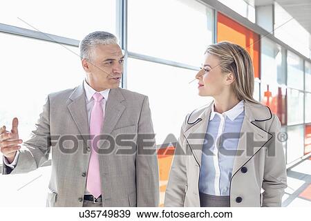 Businessman communicating with female colleague while walking in railroad station View Large Photo Image Stock Photo - Businessman communicating with female colleague while walking in railroad station. Fotosearch