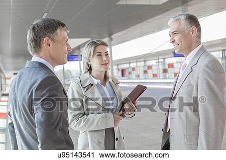 Businessman communicating with colleagues on train platform View Large Photo Image Stock Image - Businessman communicating with colleagues on train platform. Fotosearch