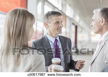 Stock Photo - Businessman communicating with colleagues on railroad platform. Fotosearch