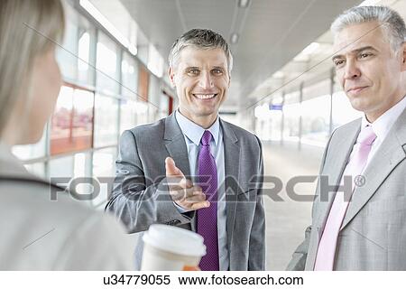 Stock Photography - Businessman discussing with colleagues at railroad platform. Fotosearch