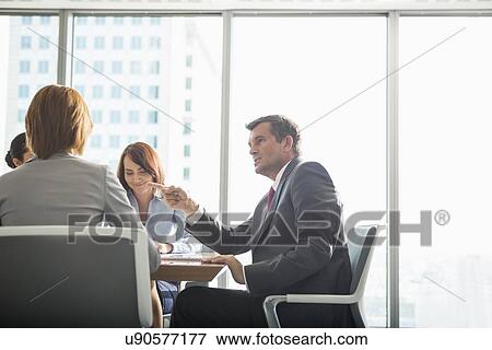 Stock Photo - Businessman discussing with female team in conference room. Fotosearch