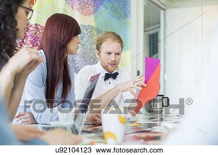 Businessman explaining documents to female colleagues in creative office View Large Photo Image Stock Image - Businessman explaining documents to female colleagues in creative office. Fotosearch