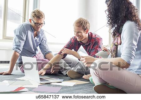 Businessman explaining plan on laptop to colleagues at creative office View Large Photo Image Stock Photo - Businessman explaining plan on laptop to colleagues at creative office. Fotosearch