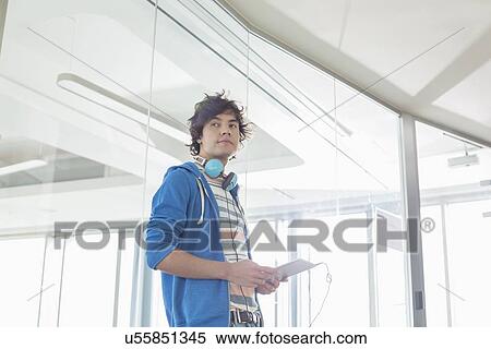 Stock Photography - Businessman looking away while holding tablet PC in creative office. Fotosearch