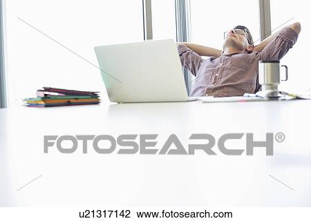 Stock Image - Businessman relaxing at desk in creative office. Fotosearch
