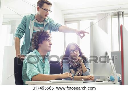 Businessman showing something to colleagues on computer in creative office View Large Photo Image Stock Photography - Businessman showing something to colleagues on computer in creative office. Fotosearch