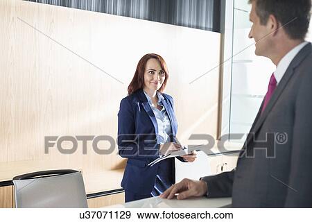 Businessman talking with receptionist in office View Large Photo Image Stock Photo - Businessman talking with receptionist in office. Fotosearch