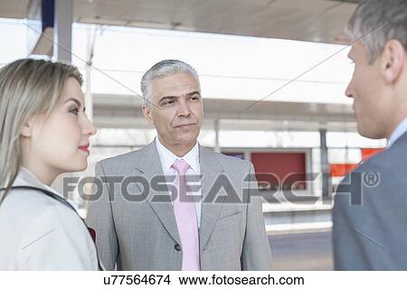Picture - Businessman with colleagues on train platform. Fotosearch