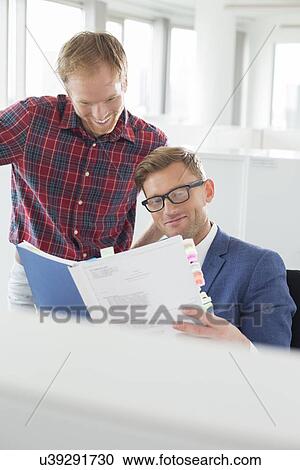 Businessmen reading file in creative office View Large Photo Image Stock Image - Businessmen reading file in creative office. Fotosearch