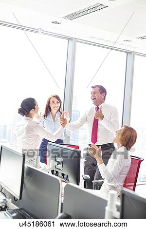 Stock Image - Businesspeople celebrating success in office. Fotosearch