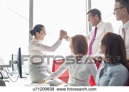 Businesspeople celebrating success in office View Large Photo Image Stock Photo - Businesspeople celebrating success in office. Fotosearch