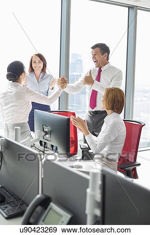 Stock Photo - Businesspeople celebrating success in office. Fotosearch