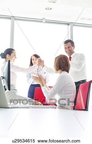 Businesspeople celebrating success in office View Large Photo Image Stock Photography - Businesspeople celebrating success in office. Fotosearch