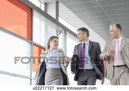 Stock Photo - Businesspeople communicating while walking on railroad platform. Fotosearch