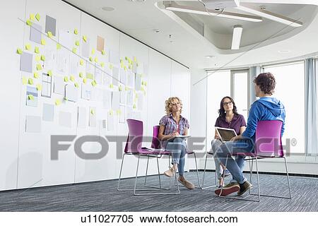 Stock Photography - Businesspeople discussing in creative office space. Fotosearch