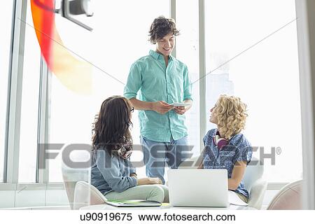 Stock Photography - Businesspeople discussing in creative office. Fotosearch