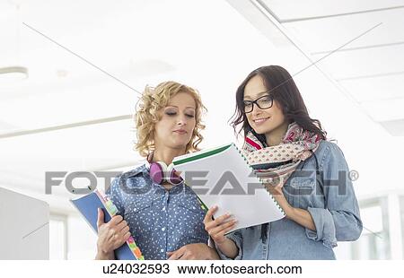 Stock Image - Businesspeople discussing over file in creative office. Fotosearch
