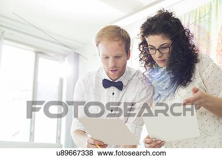 Stock Photo - Businesspeople discussing over samples in creative office. Fotosearch