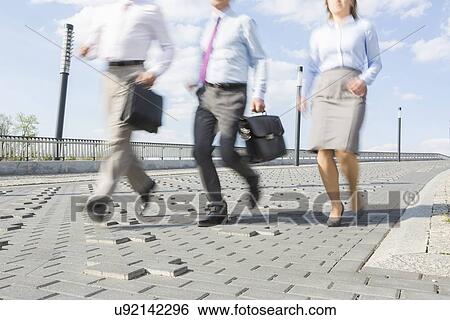 Stock Photograph - Businesspeople running on bridge. Fotosearch