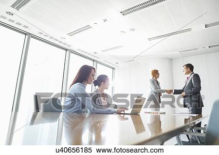Businesspeople shaking hands in board room View Large Photo Image Stock Photography - Businesspeople shaking hands in board room. Fotosearch