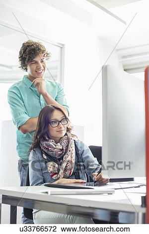 Businesspeople using desktop computer in creative office View Large Photo Image Stock Image - Businesspeople using desktop computer in creative office. Fotosearch