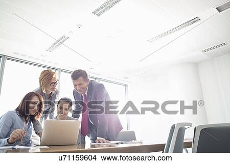 Businesspeople using laptop at conference table View Large Photo Image Picture - Businesspeople using laptop at conference table. Fotosearch