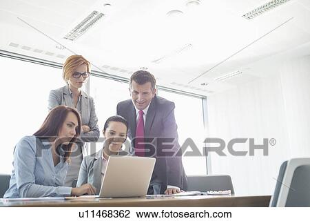 Businesspeople using laptop in conference room View Large Photo Image Stock Image - Businesspeople using laptop in conference room. Fotosearch