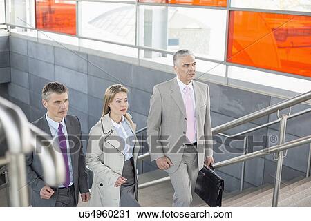 Stock Image - Businesspeople walking up stairs in train station. Fotosearch