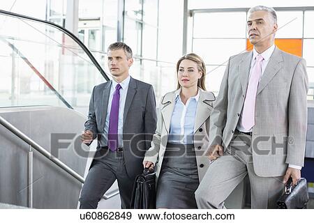 Stock Photo - Businesspeople walking up stairs in train station. Fotosearch