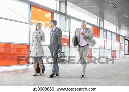 Businesspeople walking while male colleague rushing in railroad station View Large Photo Image Stock Image - Businesspeople walking while male colleague rushing in railroad station. Fotosearch