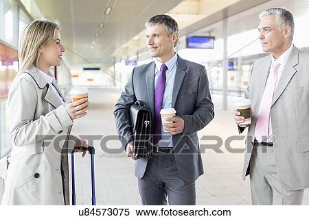 Businesspeople with coffee cups talking at railroad platform View Large Photo Image Stock Photography - Businesspeople with coffee cups talking at railroad platform. Fotosearch