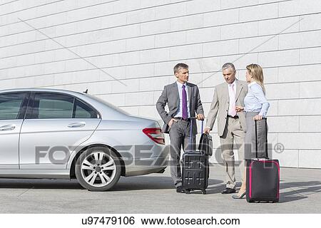 Businesspeople with luggage discussing outside car on street View Large Photo Image Stock Photograph - Businesspeople with luggage discussing outside car on street. Fotosearch