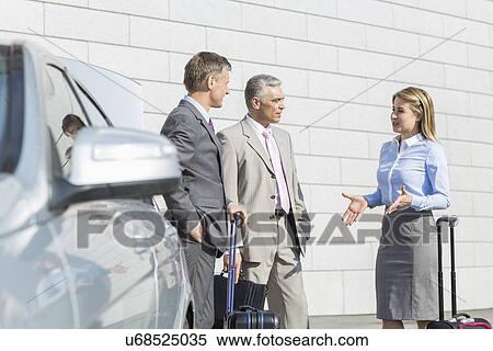 Businesspeople with luggage discussing outside car View Large Photo Image Stock Photography - Businesspeople with luggage discussing outside car. Fotosearch