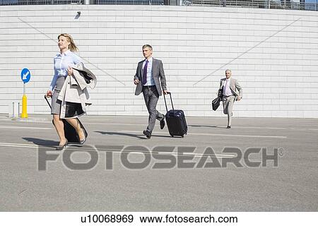 Businesspeople with luggage running on street View Large Photo Image Stock Photo - Businesspeople with luggage running on street. Fotosearch