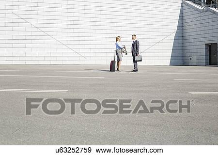 Businesspeople with luggage talking on street View Large Photo Image Stock Photo - Businesspeople with luggage talking on street. Fotosearch