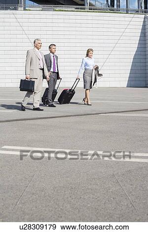 Businesspeople with luggage walking on street View Large Photo Image Stock Photo - Businesspeople with luggage walking on street. Fotosearch