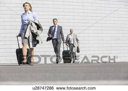 Businesspeople with luggage walking on street View Large Photo Image Stock Photograph - Businesspeople with luggage walking on street. Fotosearch