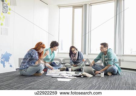 Businesspeople working on floor at creative work space View Large Photo Image Stock Photo - Businesspeople working on floor at creative work space. Fotosearch