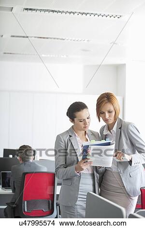 Businesswoman discussing over book in office View Large Photo Image Picture - Businesswoman discussing over book in office. Fotosearch