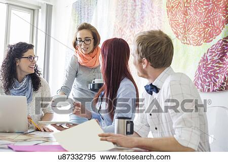 Businesswoman giving coffee to colleagues in creative office View Large Photo Image Stock Photography - Businesswoman giving coffee to colleagues in creative office. Fotosearch