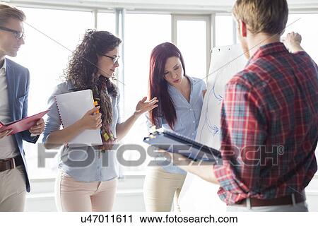 Businesswoman giving presentation to colleagues in creative office View Large Photo Image Stock Image - Businesswoman giving presentation to colleagues in creative office. Fotosearch