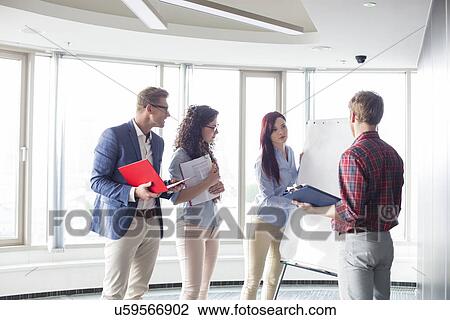 Stock Image - Businesswoman giving presentation to colleagues in creative office. Fotosearch