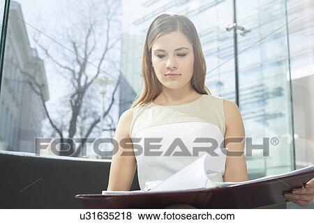 Stock Photo - Businesswoman reading file in office. Fotosearch