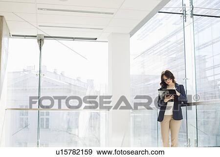 Stock Photo - Businesswoman reviewing documents in office. Fotosearch