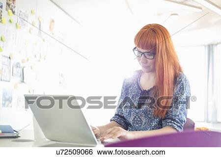 Businesswoman using laptop in creative office View Large Photo Image Stock Photograph - Businesswoman using laptop in creative office. Fotosearch
